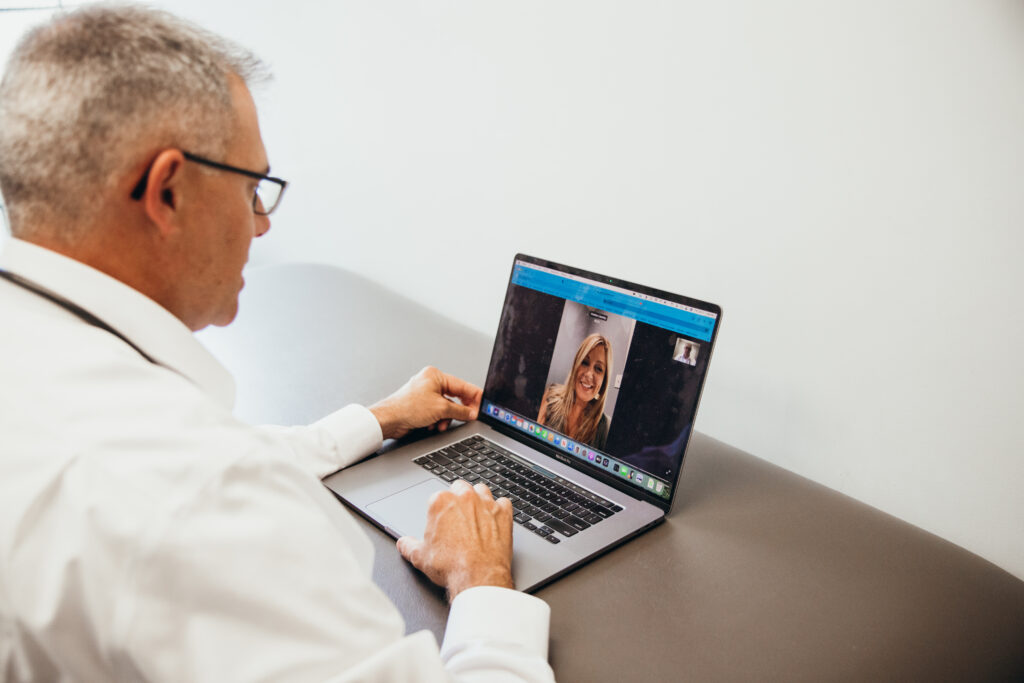 Doctor Wheeler meeting with patient virtually over webcam on laptop