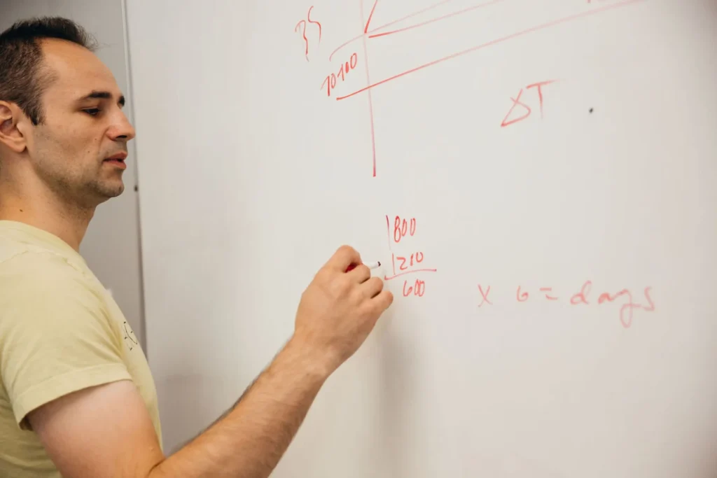 someone writing mathematical formulas on a whiteboard